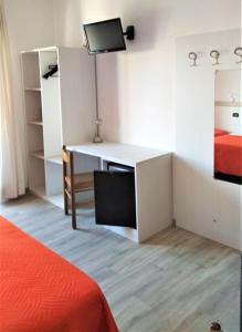 a bedroom with a bed and a desk with a television at Hotel Ciao Bed & Breakfast in Lignano Sabbiadoro