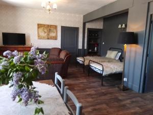 a living room with a bed and a room with a couch at L'ancienne Gendarmerie in Saint-Laurent-sur-Gorre