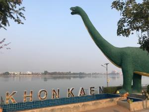 una statua di dinosauro davanti a un corpo d'acqua di Grace Hostel a Khon Kaen