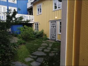 uma casa amarela com uma porta cinzenta ao lado de um quintal em Sjarmerende historisk leilighet midt i Tromsø em Tromsø