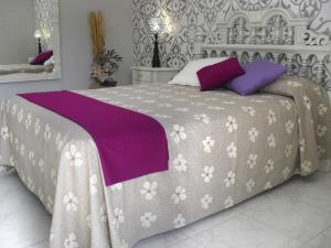 a bed with purple and white sheets and pillows at Casa Vacanze Milosa in Terme Vigliatore