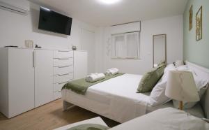 a white bedroom with a bed and a tv at Alice al Mare in Pescara