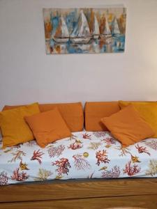 ein Sofa mit orangefarbenen Kissen und ein Gemälde an der Wand in der Unterkunft casa vacanze Ugo e Betty in Sanremo