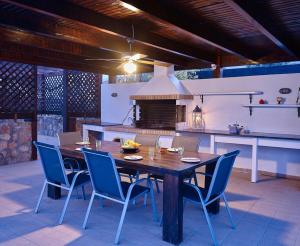 a kitchen with a wooden table and blue chairs at Ferienhaus in Vlycha Beach mit privatem Pool und herrlicher Aussicht in Líndos