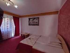 een kleine slaapkamer met een bed en een raam bij Pensiunea Dana Olteanu in Moieciu de Sus