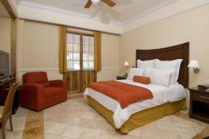 a bedroom with a large bed and a red chair at Hacienda Real del Caribe Hotel in Playa del Carmen