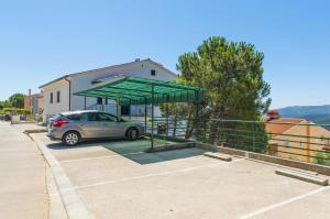 een auto geparkeerd op een parkeerplaats met een groene luifel bij Ferienwohnung für 2 Personen ca 27 qm in Rabac, Istrien Bucht von Rabac - b58159 in Rabac