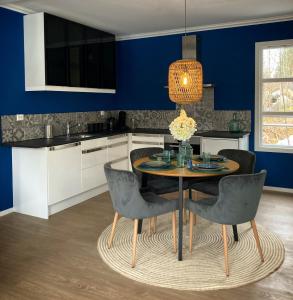 d'une cuisine avec une table et des chaises et des murs bleus. dans l'établissement BB Grindhuset, à Larvik