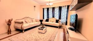 a living room with two couches and a tv at Cityscape Retreat Apartment in Sharjah +15 photos