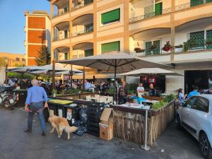 a man with a dog standing next to an outdoor market at corso francia suite in Rome