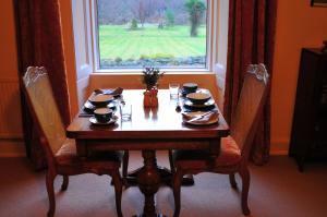 a dining room table with chairs and a window at Achintee Farm Guest House in Fort William