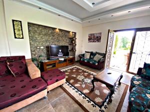 uma sala de estar com um sofá e uma televisão em فيلا خاصة مفروشة بالكامل em Qaryat Shākūsh