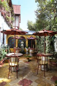 un patio al aire libre con mesas, sillas y sombrillas en Boutique Hotel Antinea, en Quito
