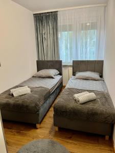 two beds in a room with a window at Przytulny apartament in Augustów