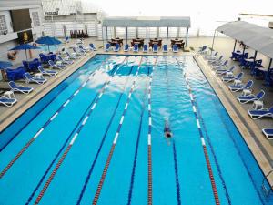 a person swimming in a swimming pool with chairs at Zamalek Army Hotel in Cairo