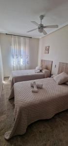 a bedroom with two beds and a ceiling fan at Apartamento Ribera Real II in Córdoba