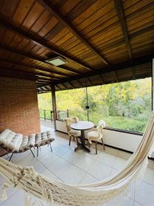 a porch with a hammock and a table and chairs at Estalagem Mandeville in Monte Verde