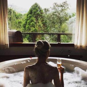 a woman sitting in a bath tub holding a glass of wine at Estalagem Mandeville in Monte Verde