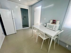 cocina con mesa blanca, sillas y microondas en Grace Container homes, en Cedar Grove