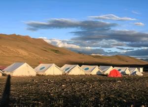 um grupo de tendas num campo com uma colina em Mantri Bai Camping Site Deosai em Skardu