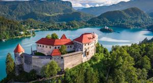 an castles in the middle of a lake with mountains at Sunshine apartment Bled in Bled