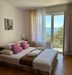 a bedroom with a large bed with a large window at Helen Apartments in Crikvenica