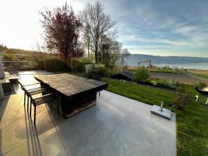 un patio con una mesa de madera y un banco en Besoin d'un séjour Détente & Tranquillité avec une vue panoramique ?, en Châtillon