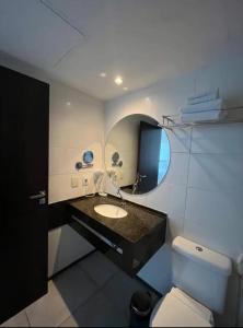 a bathroom with a sink and a toilet and a mirror at Suíte 511, do Hotel Ritz Suítes in Maceió