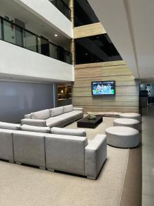 a living room with couches and a flat screen tv at Suíte 511, do Hotel Ritz Suítes in Maceió