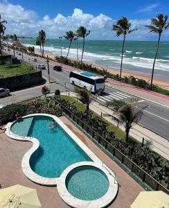 a large swimming pool next to the beach with a bus at Suíte 511, do Hotel Ritz Suítes in Maceió