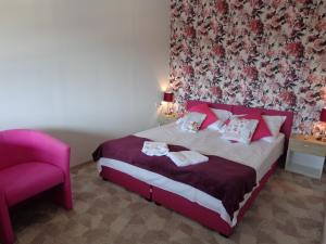 a bedroom with a bed and a pink chair at Noclegi-SKAŁKA in Olsztyn