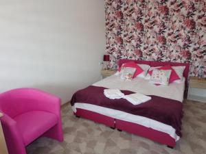 1 dormitorio con cama rosa y silla rosa en Noclegi-SKAŁKA, en Olsztyn