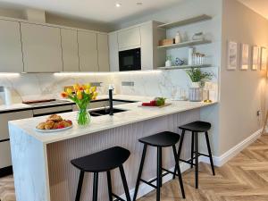 a kitchen with two bar stools and a counter with flowers at Number 8 Croft House in Pembrokeshire