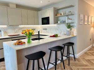 una cocina con 2 taburetes y una barra con flores en Number 8 Croft House Tenby, en Tenby