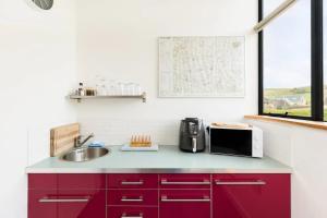a kitchen with red cabinets and a sink at Pass the Keys Vyners Studio Long Compton · Self-Contained 1 Bedroom Studio in Long Compton