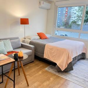 ein Schlafzimmer mit einem Bett, einem Sofa und einem Fenster in der Unterkunft Studio maravilhoso PUC in Porto Alegre