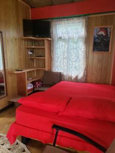 Cama roja en habitación con ventana en Lovers View, en Giraudel