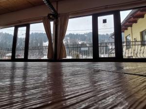 an empty room with a large window and a wooden floor at Pensiunea Dana Olteanu in Moieciu de Sus