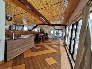 a kitchen with wooden ceilings and a dining room with tables at Pensiunea Dana Olteanu in Moieciu de Sus