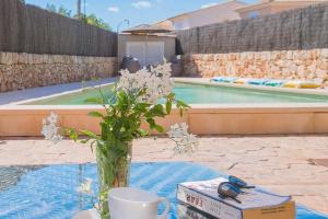 un vase de fleurs posé sur une table à côté d'une piscine dans l'établissement Ferienhaus mit Privatpool für 6 Personen ca 120 m in Sa Rapita, Balearen Mallorca, à Sa Ràpita