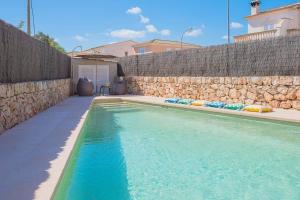 - une piscine à côté d'un mur en pierre dans l'établissement Ferienhaus mit Privatpool für 6 Personen ca 120 m in Sa Rapita, Balearen Mallorca, à Sa Ràpita