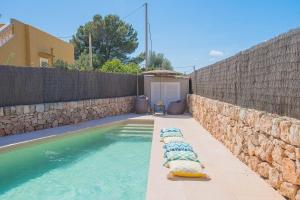 uma piscina com duas espreguiçadeiras ao lado de uma parede de pedra em Ferienhaus mit Privatpool für 6 Personen ca 120 qm in Sa Rapita, Mallorca Südküste von Mallorca em Sa Ràpita
