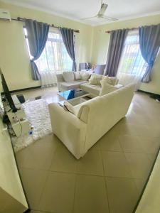 un soggiorno con divani bianchi e tende blu di A private self contained room in a home away from home a Dar es Salaam