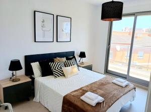 a bedroom with a bed with two lamps and a window at Apartamento Luna con terraza y vistas al mar in Playa Oliva Nova