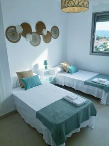 two beds in a white room with a window at Apartamento Luna con terraza y vistas al mar in Playa Oliva Nova
