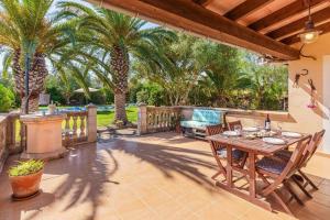 a patio with a table and chairs and palm trees at Haus mit Pool auf Mallorca in Manacor +14 photos