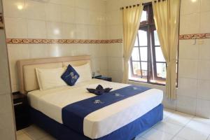 a bedroom with a bed with blue and white sheets and a window at LH - Norm House in Kuta