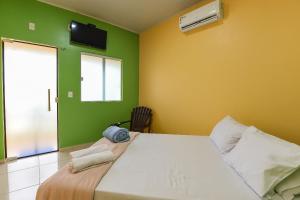 een slaapkamer met een groot wit bed en groene muren bij Suíte Sapoti - Quarto Casal in Barreirinhas