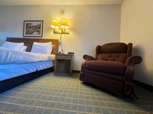 a hotel room with a bed and a chair at Dakota Inn in Minot