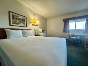 a hotel room with a large white bed and a table at Dakota Inn in Minot